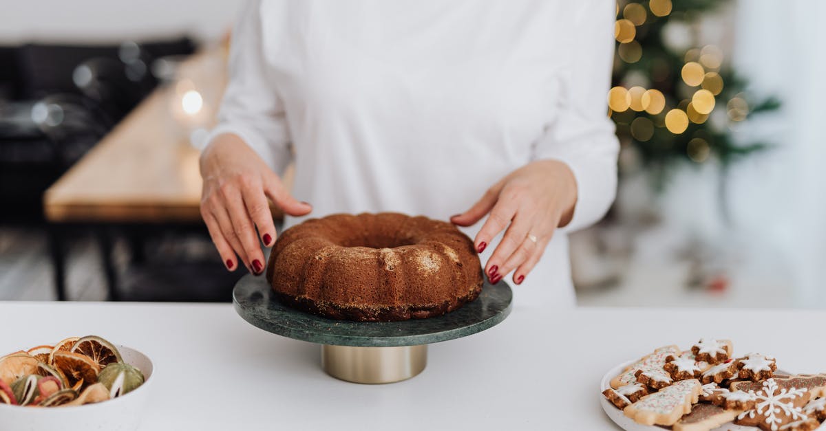 cake undercooked or too wet? - Person in White Long Sleeve Shirt Holding Brown Pastry on Black Round Tray