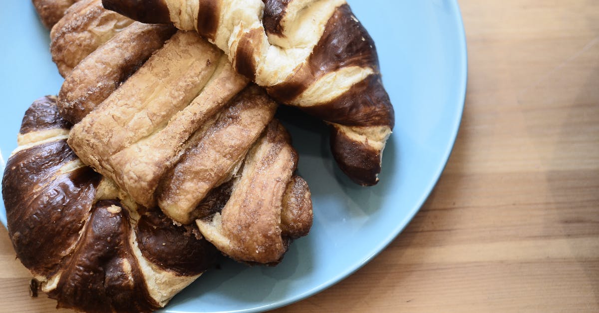 Cake with an impenetrable crust? - Top view of delicious crusty croissants with chocolate topping on wooden table in bakery