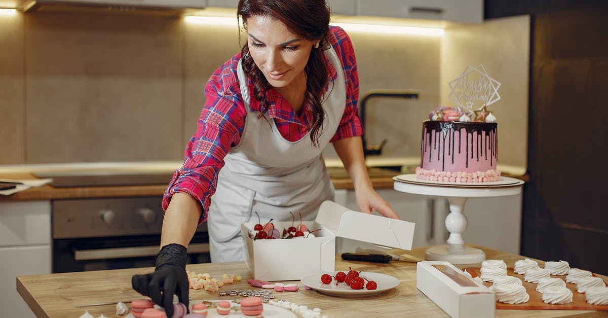 Cake with ganache on top going to the freezer - Focused woman decorating cake with macaroons in kitchen