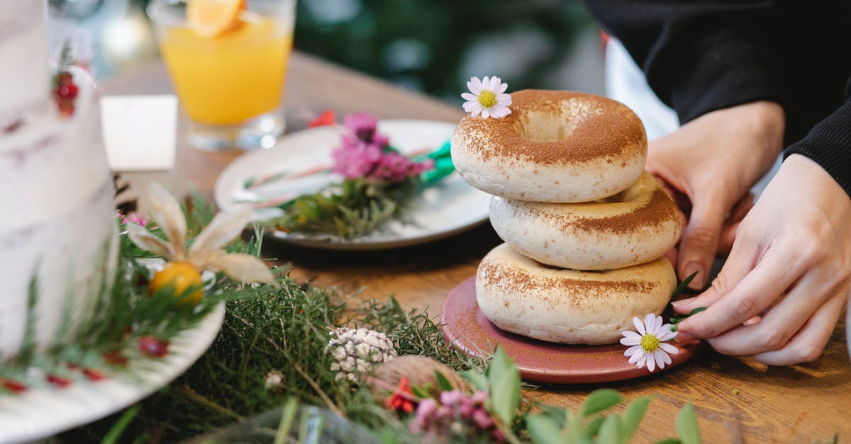 Cake without baking powder made 2 layers in a cake. Why? - Faceless cook with pile of bagels decorated with cinnamon powder and blossoming chamomiles on plate during New Year holiday indoors