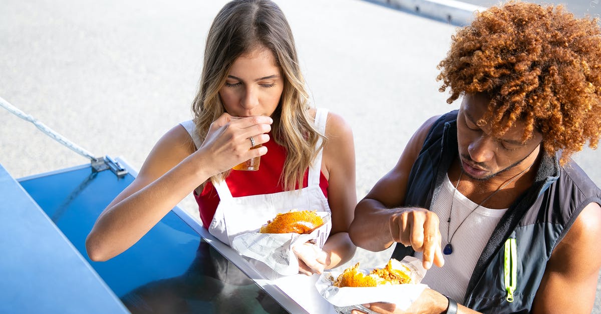 Calories in toast vs bread - High angle of diverse couple eating unhealthy food made of buns and fried meat at counter