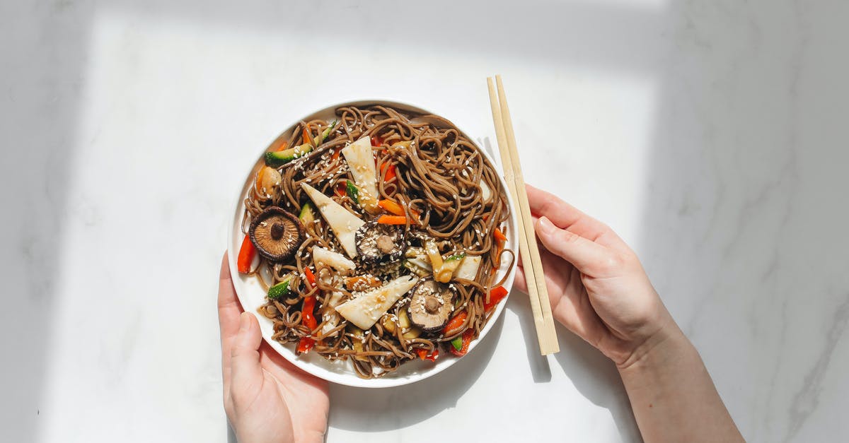 Calories pre-cooked vs cooked - Person Holding Plate With Noodle Dish and Chopstick