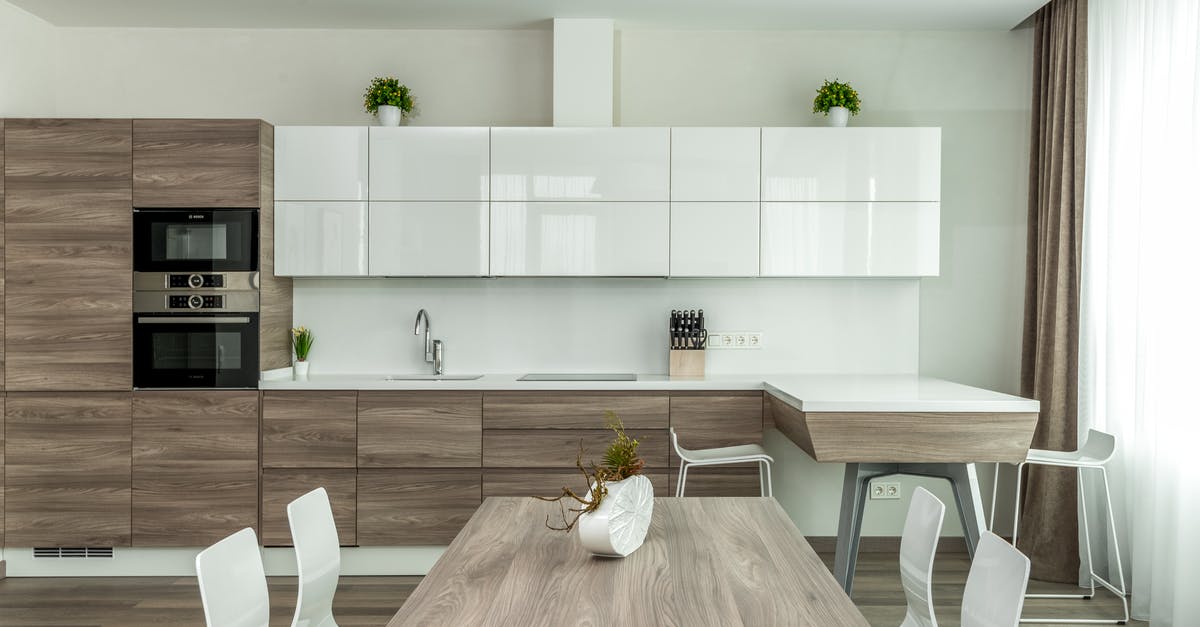 Can a large number of eggs be scrambled in a pot? - Modern open plan kitchen with white glossy and wooden cabinets and dining table with white chairs near in light apartment