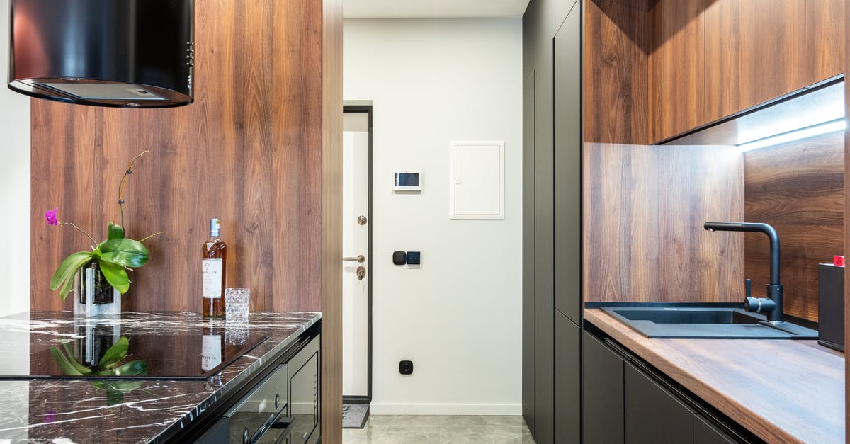 Can a microwave oven cook chicken? - Modern kitchen with hob built in table with flower and bottle of liquor against tap in house