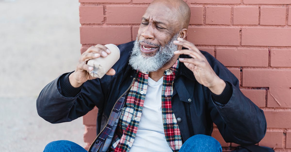 Can alcohol evaporation get you drunk? - African American bearded male in casual outfit raising arms with beer can while resting on street near brick wall