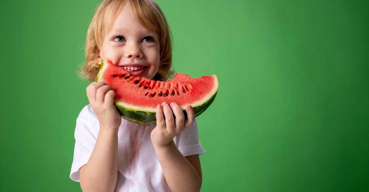 Can any harm come of eating watermelon seeds? - Girl in White Shirt Holding Green Watermelon