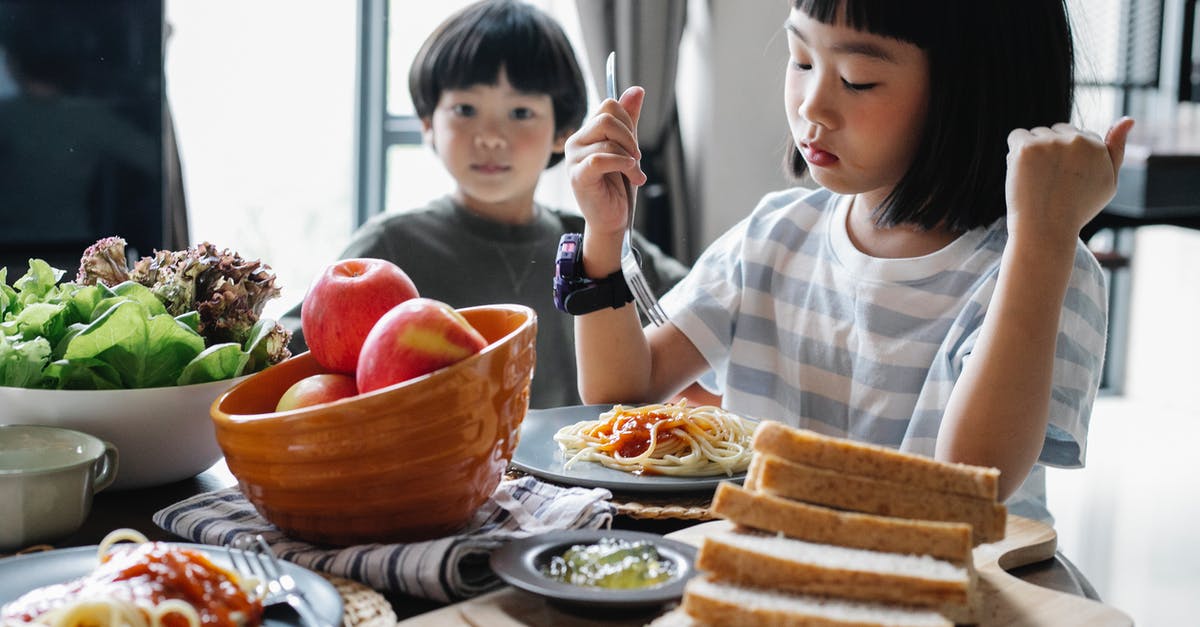 Can Apple Butter be substituted for Apple Sauce in baking? - Serious little Asian girl eating delicious pasta with cute brother while sitting at table with healthy salad and apples on sunny day