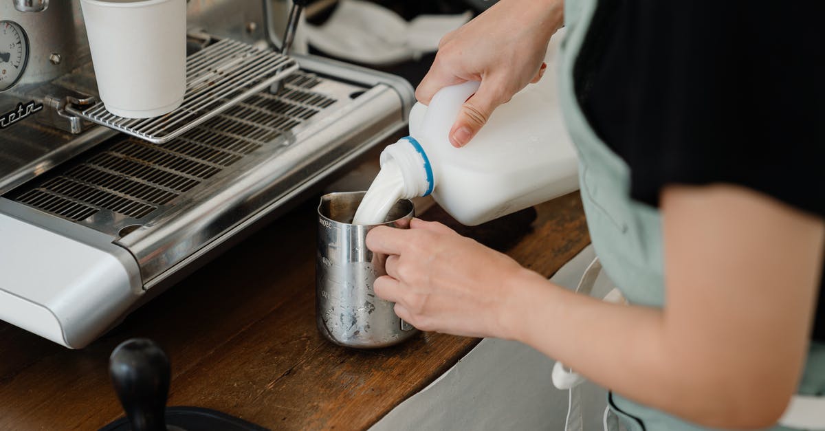 Can bean-to-cup machine make quality espresso/cappuccino? - Side view of crop unrecognizable cafe worker pouring fresh milk into big stainless still cup while preparing beverage at counter with coffee machine in modern cafe