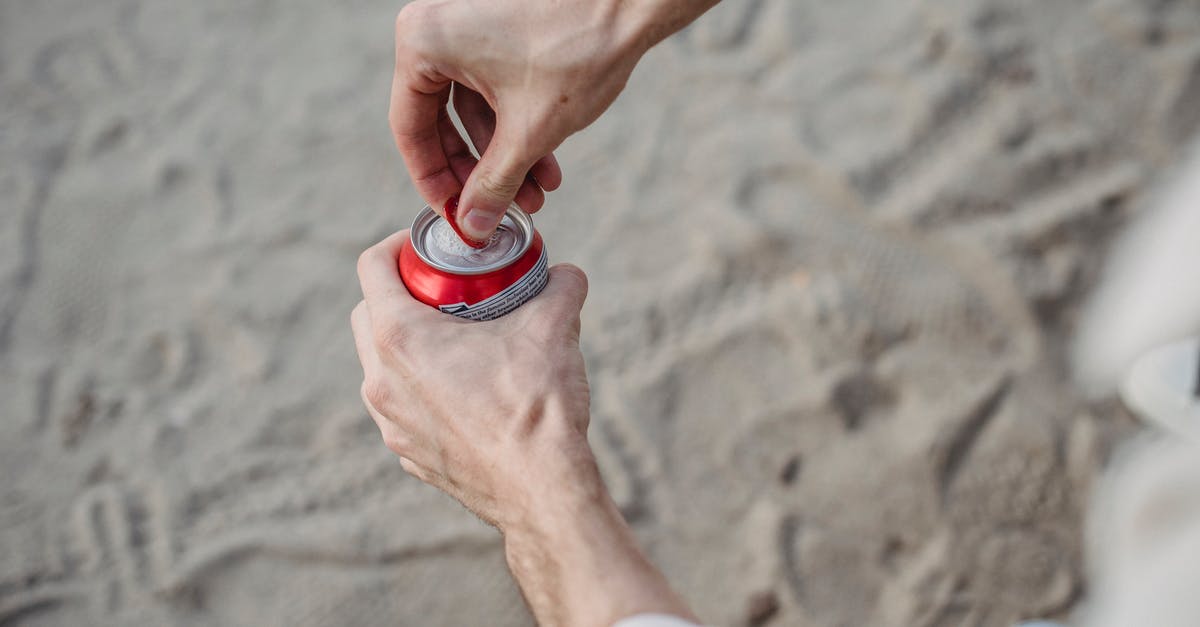 Can beef stew be reheated several times? - From above of crop anonymous male opening can of drink standing on sandy beach