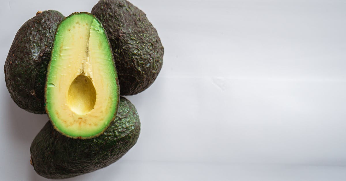 Can bright green avocados be ripe? - Top view of heap of fresh avocados with rough dry skin and colorful tender pulp on white background