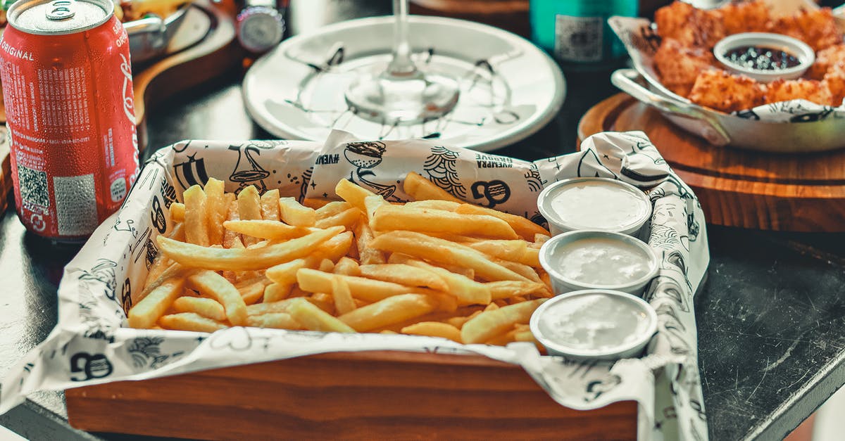 Can excess oil make french fries soggy? - A Fries with Dips on a Wooden Tray Near the Red Can