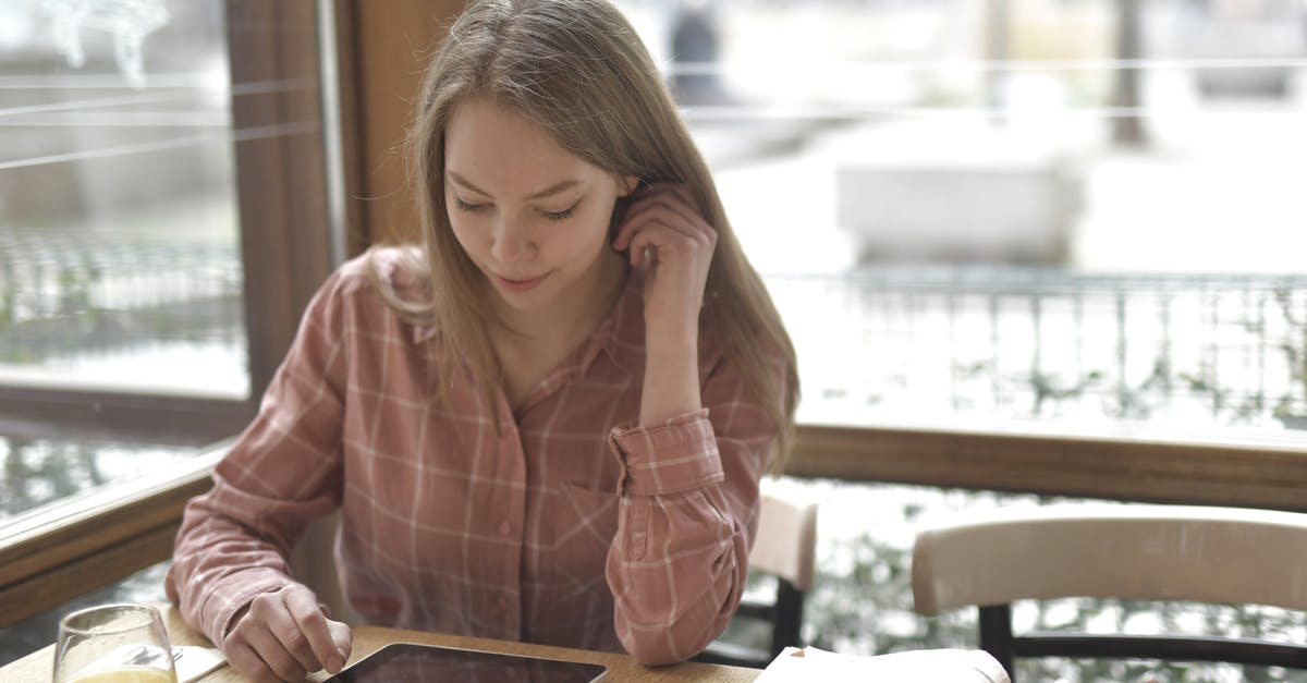 Can expired orange juice be used in baking [duplicate] - Cheerful concentrated female in checkered shirt sitting at table with glass of fresh juice and newspaper while using tablet