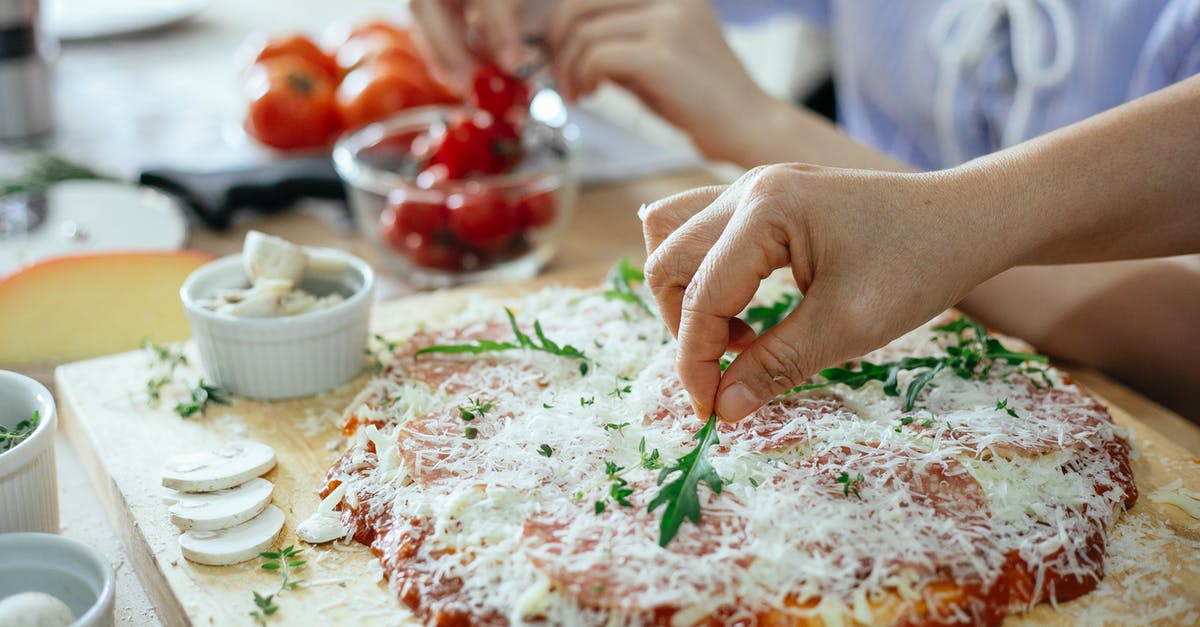 Can fresh basil cause tomato sauce spoilage? - Women making homemade pizza in kitchen