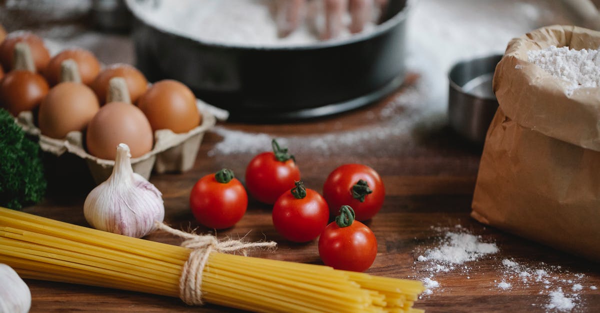 Can handmade pasta be more than just flour + eggs? - High angle of cherry tomatoes eggs garlic and spaghetti on table with crop chef kneading dough in baking dish