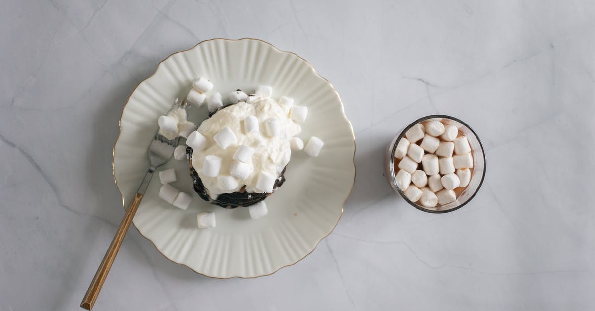 Can I add cocoa butter to white chocolate chips to promote a smoother melt? - Top view of plate and fork with delicate white marshmallow and chocolate topping near cocoa Can I add cocoa butter to white chocolate chips to promote a smoother melt? - Top view of plate and fork with delicate white marshmallow and chocolate topping near cocoa