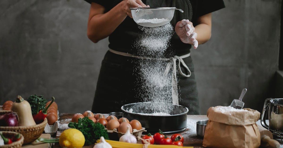 Can I add lemon zest to a shortbread cookie recipe? - Crop unrecognizable cook adding flour into stainless baking dish while cooking meal with spaghetti cherry tomatoes garlic herbs and lemon