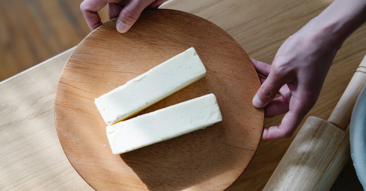 Can I always use butter instead of margarine when baking? - Close-Up Shot of a Person Holding a Wooden Plate with Sliced Butters