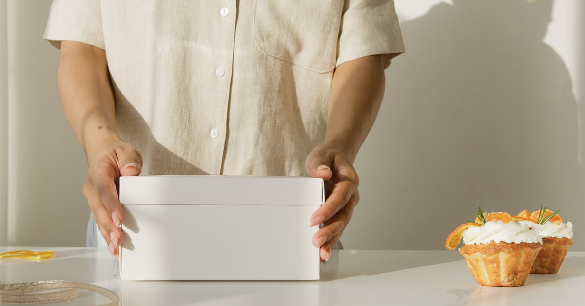 Can I bake a christmas cake in a cardboard box? - Person in White Button Up Shirt Holding White Box