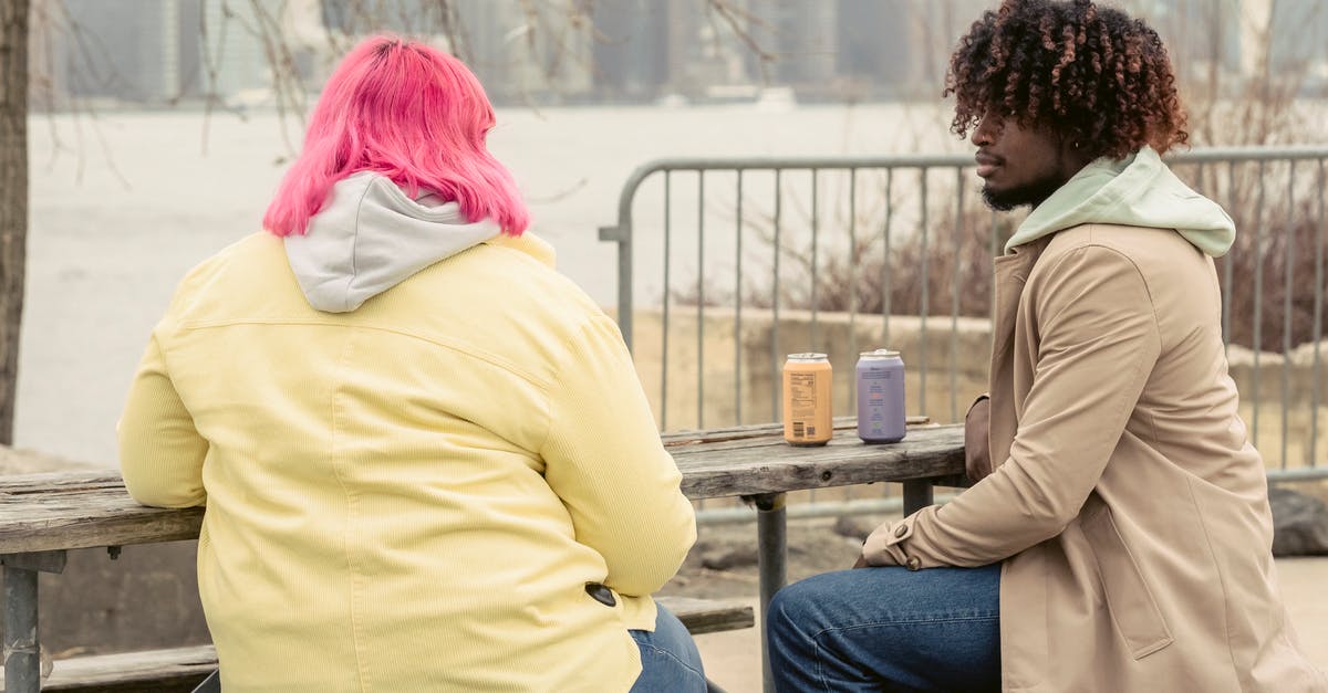 Can I build a fond with seitan? - Stylish African American man and faceless woman with pink hair sitting at wooden table with cans of drinks while spending time on waterfront