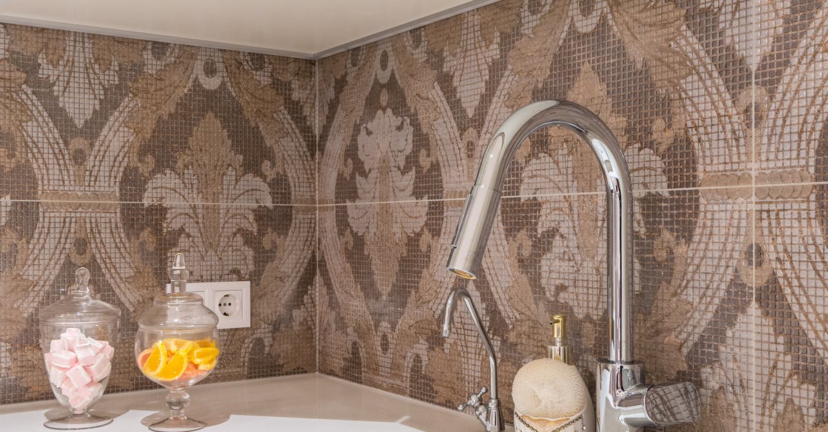 Can I clean enameled cast iron with steel wool? - Contemporary kitchen stone counter with undercounter sink and shiny metal faucets at beige and brown tiled backsplash with ornament