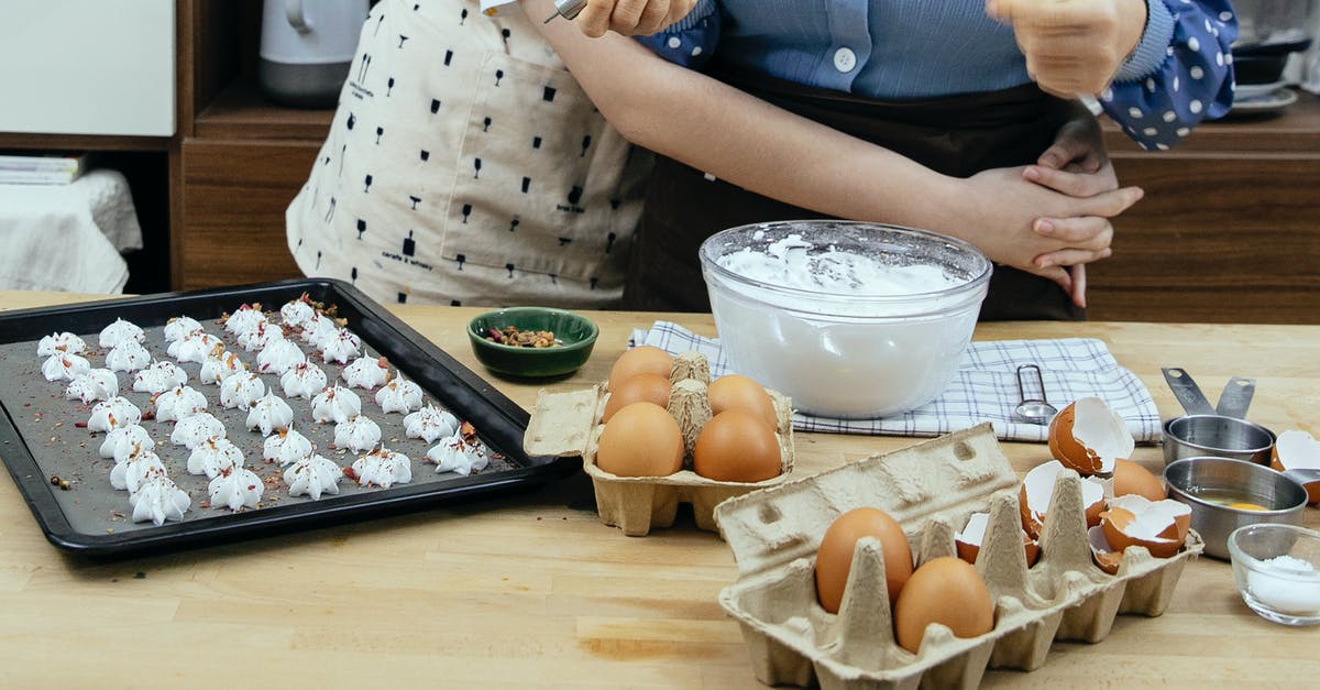 Can I cook Meringue on tin foil rather than Baking paper? - Crop anonymous adolescent embracing cook while preparing meringue cookies with condiments at table in house kitchen