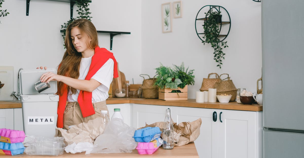 Can I defrost chicken to separate then refreeze? - Young responsible female standing in kitchen and putting tin can into bucket while sorting trash