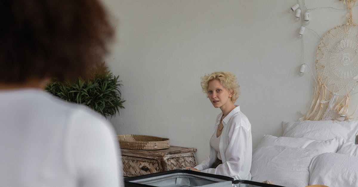 Can I leave boneless chicken breast flat in freezer overnight? - Content lady with blond hair preparing to leave while sitting on bed near white wall in bedroom with crop female friend with dark hair