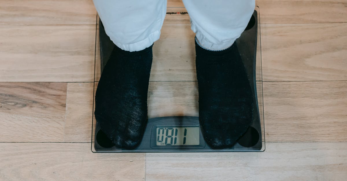 Can I measure solids-not-fat using nutrition facts only? - From above of crop unrecognizable plus size person in casual clothes standing on weighing scale on wooden floor