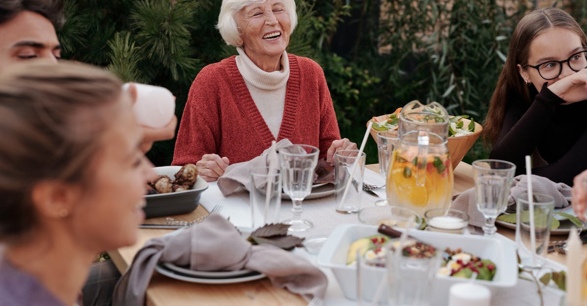 Can I safely clean/eat harvested foods that have aphids on them? - Smiling elderly woman with family and friends enjoying dinner at table backyard garden