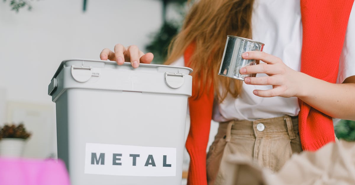 Can I save peanut oil from turkey fryer after rain? - Low angle of female putting tin can into bucket for metal trash for recycling litter