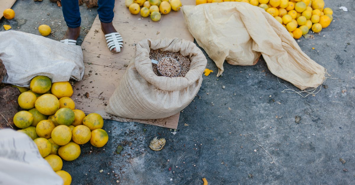 Can I sprout grains/legumes/seeds I buy in bulk from whole foods? - From above of crop faceless seller near pile of ripe oranges on ground and bag of grains at bazaar