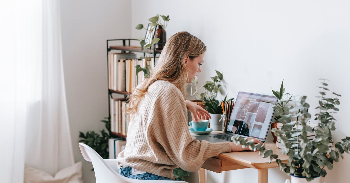 Can I use a terracotta pot to bake a pie? - Side view of attentive female remote employee with cup of tea watching photo gallery on netbook screen at desk in house