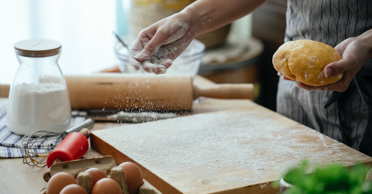 Can I use flour to make a carrot soup more thick? - Crop faceless female baker in apron sprinkling wheat flour on cutting board to roll out fresh dough in modern kitchen
