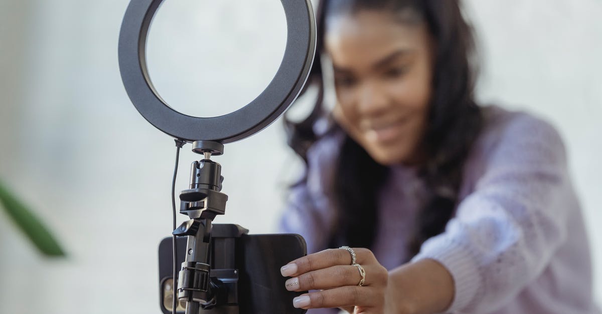 Can I use live yoghurt to kick-start fermentation? - Cheerful young African American female blogger in stylish sweater smiling while setting up camera of smartphone attached to tripod with ring light before recording vlog