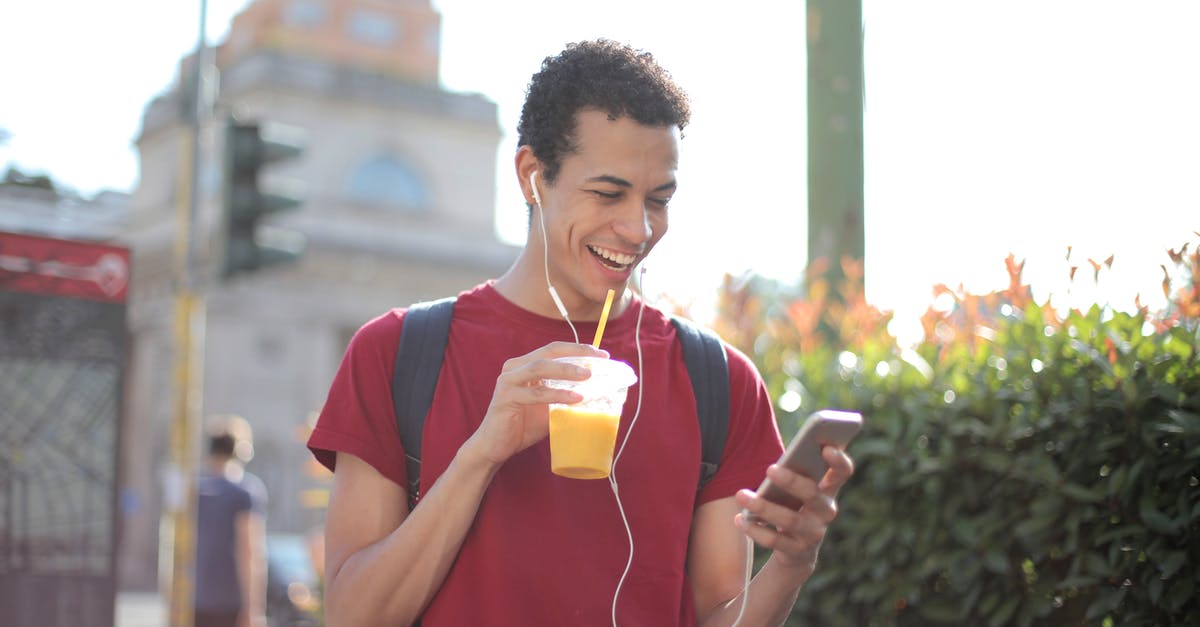 Can I use orange juice to pasteurize egg whites? - Happy ethnic guy in casual wear and with backpack having cup of fresh juice using smartphone while standing on street and listening to music