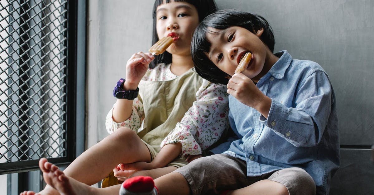 Can Ice Cream Maker Wall be Too Cold? - Positive Asian children in casual clothes sitting on floor and eating yummy ice creams