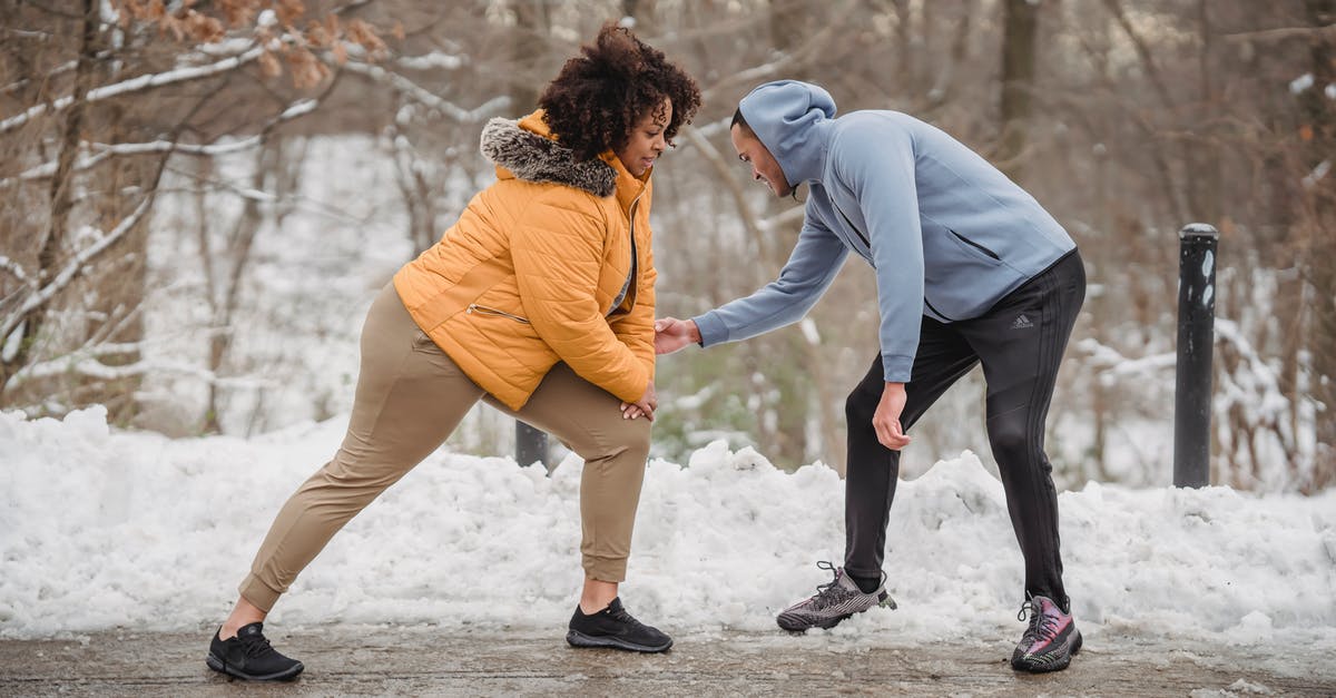 can ice help with spicy food? - Professional instructor helping African American female doing exercises on frozen path of winter park