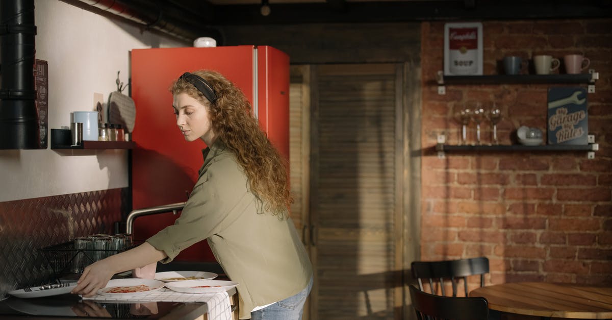 Can some dishes be washed with only water? - Woman in Gray Long Sleeve Shirt and Blue Denim Jeans Standing Beside Kitchen Counter