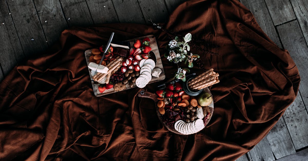 Can tempered chocolate be seeded with a different chocolate? - Overhead view of various sweets and snacks with fruits on plate and cutting board on dark brown fabric on wooden floor in daytime