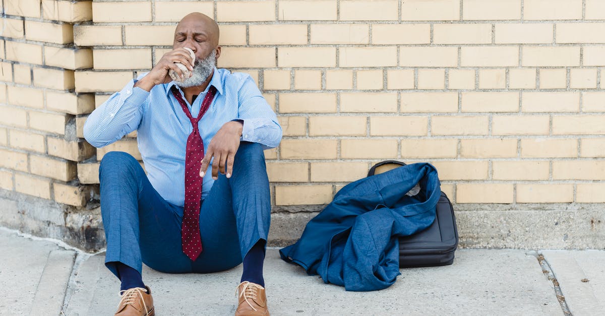 Can the Cadbury Creme Egg's filling be bought independently? - Full body of mature African American bearded businessman in blue trousers and light shirt with maroon tie sitting on ground at brick wall and drinking beverage from tin can