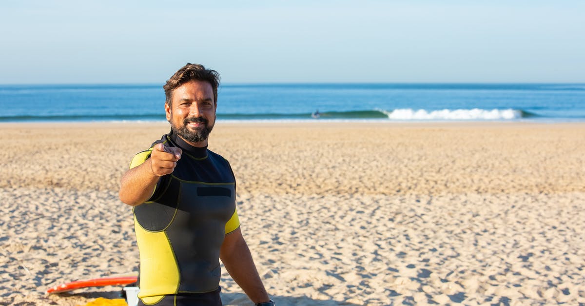 can you cool manicotti noodles off completly before stuffing - Happy male in diving suit looking and pointing at camera while standing on beach in bright sunny day