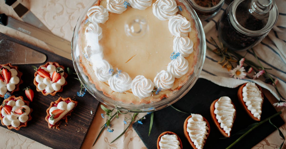 Can you cover an angel food cake with fondant? - Top view of appetizing cake and desserts with whipped cream near knives and flowers on table