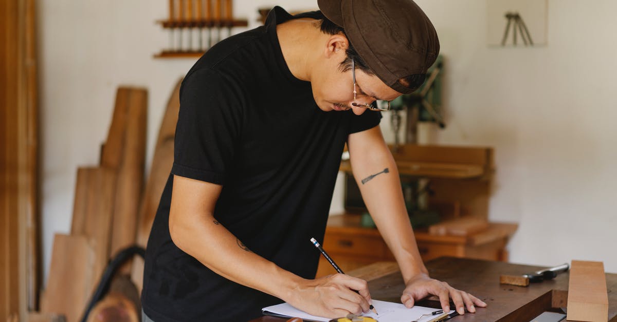 Can you estimate how long it takes to reduce a liquid? - Side view of Asian man in casual clothes and eyeglasses bending on table and taking notes by pencil while working in joinery