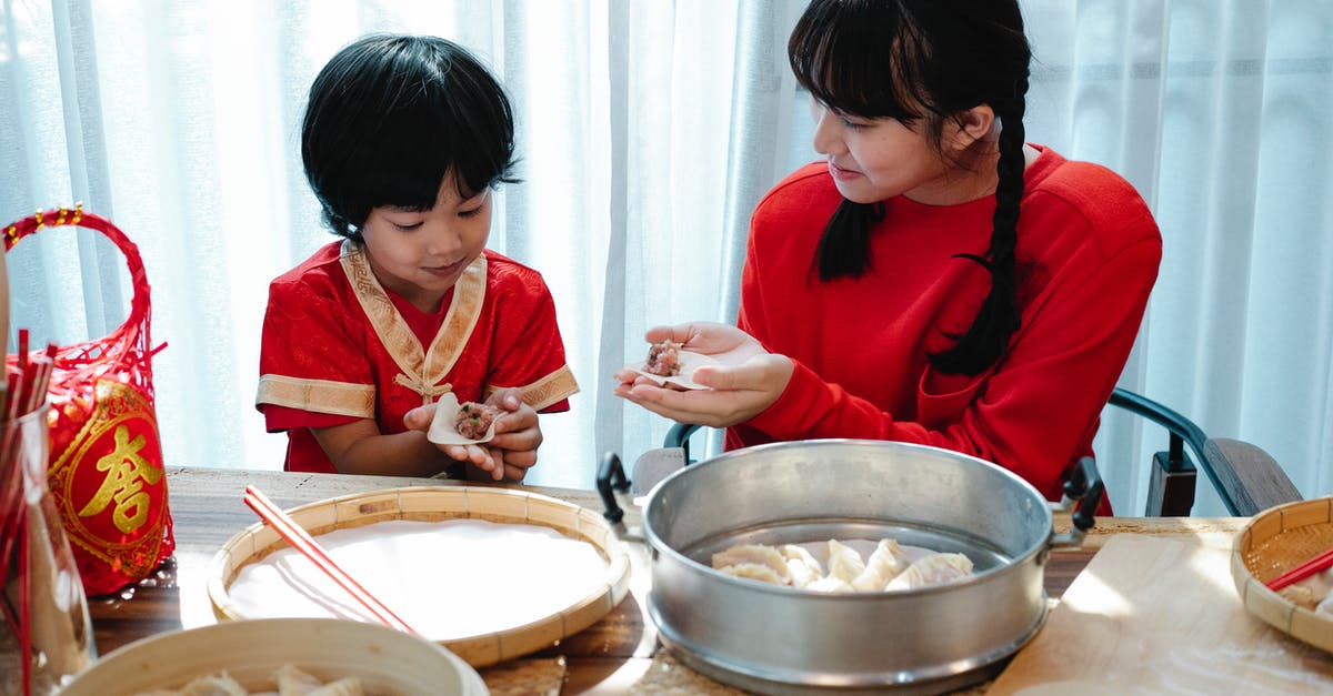 Can you fold dough during autolyse? - Happy Asian teenage girl with dark hair smiling and helping adorable little brother to fold traditional Chinese dumplings during dinner preparation in kitchen