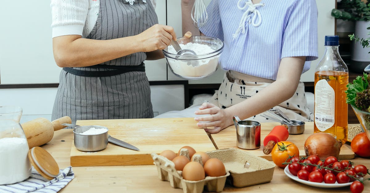 Can you make stew without onions? - Unrecognizable female cooks with bowl of flour standing at table with cutting board and various ingredients in kitchen while making dough