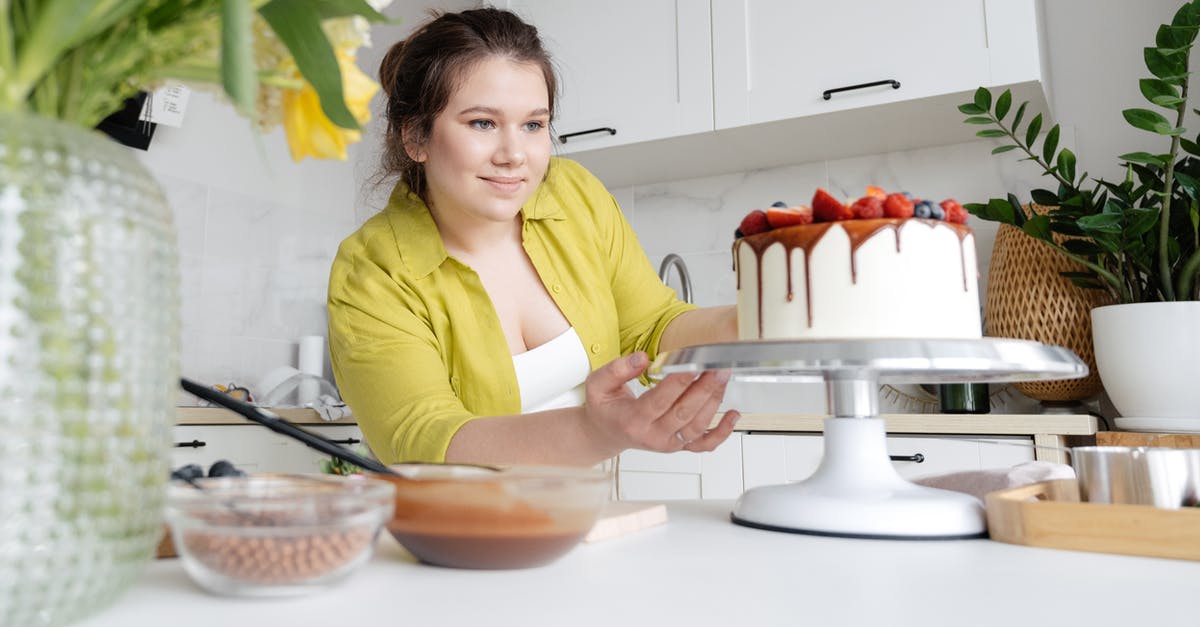 Can you partially cook soup/stew and finish cooking it later? - Smiling young female confectioner in casual clothes finishing decoration of tasty cake with chocolate glaze and berries