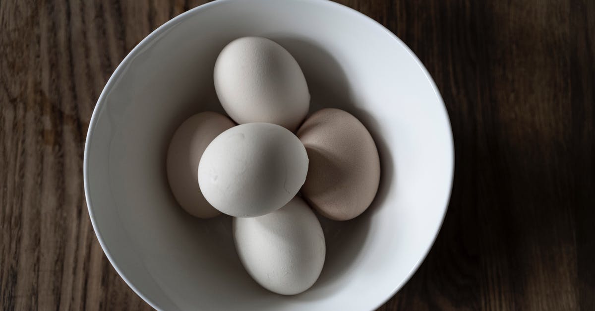 Can you refreeze chicken after it has been cooked from frozen - Top view of pile of white cooked chicken eggs in ceramic bowl on wooden table at home