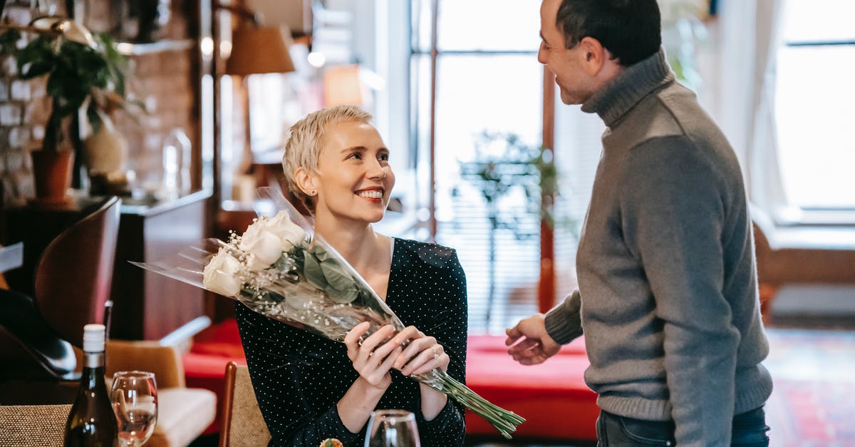 Can you substitute white wine with rose? - Happy couple having romantic dinner while man giving bouquet of white roses to woman near table with wine bottle and glasses near plate with pasta and looking at each other