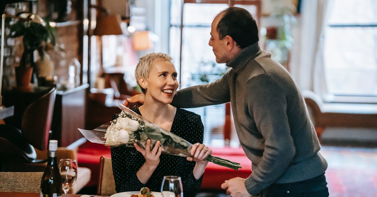 Can you substitute white wine with rose? - Couple having romantic dinner while man giving bouquet of white roses to woman near table with plate with pasta near wine bottle and glasses while looking at each other