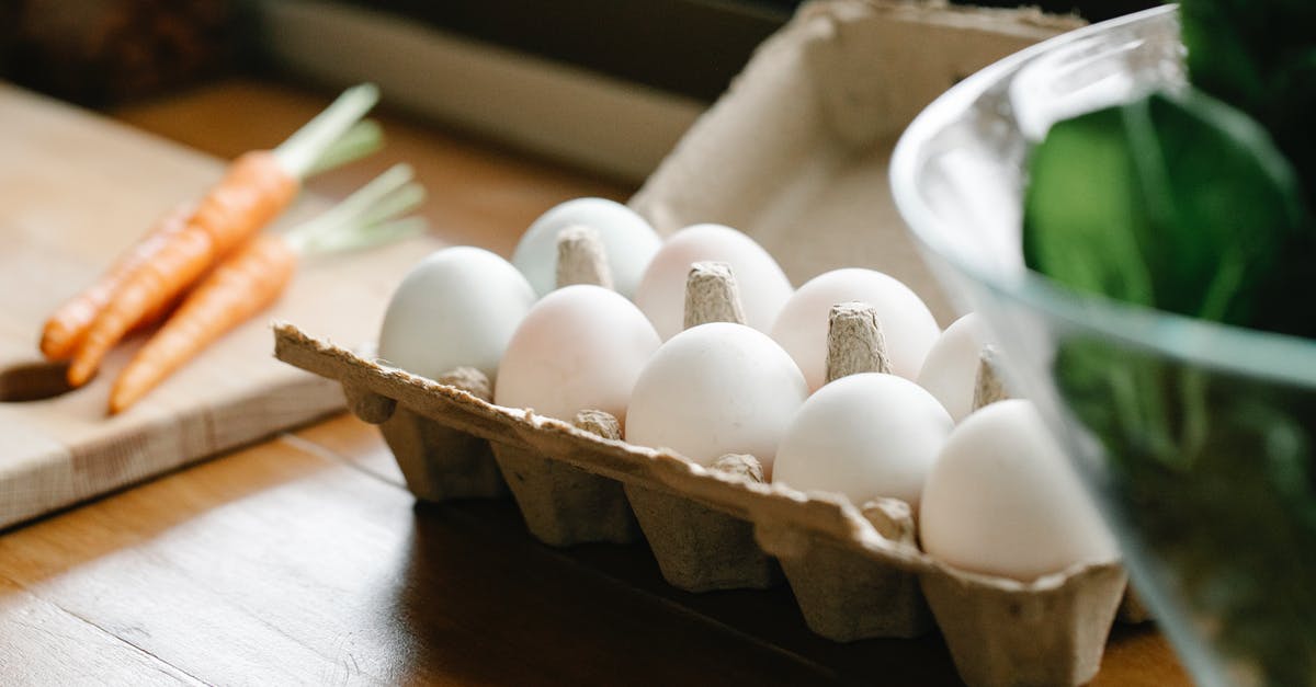 Can you substitute whole eggs for egg whites in baking? - Carton box with white organic eggs placed on kitchen counter near chopping board with carrots